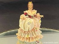 Front view of the lace lady figurine showing the detailed layering of the pink dress and lace apron with flowers.