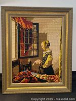 Frontal photo of large needlepoint tapestry artwork showing lady reading a letter with wooden frame.