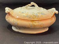 Side angled view of early 20th century Limoges porcelain tureen featuring peach-colored gradient, floral patterns, and detailed sculpted handles.