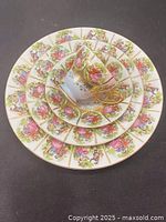 Overhead view of all four pieces stacked: dinner plate, cake plate, saucer, and cup showing decorative patterns and gold rims
