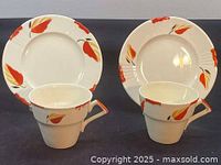 Two hand painted Myott teacups and matching saucers showing leaf motif around rims in red and orange on white ceramic.