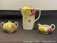 Full coffee set showing pot, sugar bowl, and creamer with floral hand painted designs