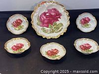 Set of one large and five smaller hand painted porcelain bowls with pink and red cabbage rose decoration and gold trim.