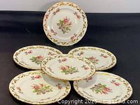Five Royal Chelsea side plates arranged with one elevated and four surrounding, showing floral and gold leaf pattern.