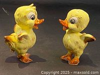 Photo showing two yellow ceramic duck figurines with wings folded, each about 5 inches tall, hand-painted with orange beaks, feet, and brown shaded details.