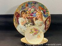 Plate with detailed scene of two young girls with a cat beside a table, surrounded by colorful flowers and gold rim