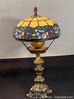 Full view of Tiffany style table lamp showing stained glass shade with floral pattern and ornate brass base.