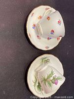 Teacup with small pink, red, and blue floral pattern and matching saucer showing detail of floral design and gold trim.