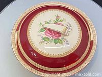 Top view of Wedgwood plate showing floral hand painted design with red and gold border
