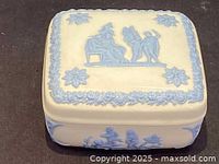 Top view of Wedgwood trinket box showing classical figures and floral border in blue jasperware on white ceramic base.