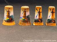 Front view of four hand painted windmill salt and pepper shakers showing detailed paintwork and shapes.