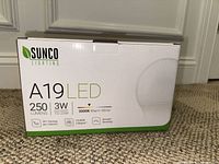 Front view of the Sunco Lighting A19 LED light bulb box showing bulb specs: 250 lumens, 3W (equivalent to 25W), 3000K warm white color temperature, smooth dimming, and 21,000 hours lifespan.