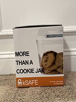 Front of box showing the kSafe container with cookies inside, large display on lock and branding 'More Than A Cookie Jar'.