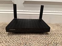 Front view of Linksys MR7310 black wireless router showing vented top and two antennas.