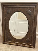 Full frontal photo of the rectangular wood framed wall mirror with oval mirror and shell decorations on each corner, showing condition and design details.