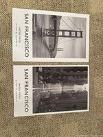 Two black and white prints of San Francisco landmarks and street scene laid flat on a carpet, showing details of the print and typography.