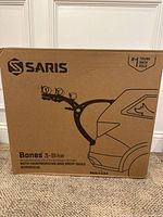 Photo of intact Saris Bones 3-Bike trunk rack box showing branding and key features