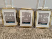 Three new Studio Décor Belmont 11x14 beige wooden picture frames with protective corner covers, showing front view on carpet floor.