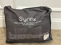 Packaged Syrinx weighted blanket in a branded black soft carry bag with printed instructions and product information.