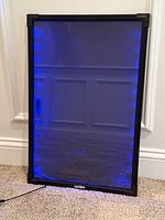 Front view of the LED glass drawing board lit in blue light, showing black metal frame and glass surface.