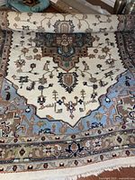 Partially unrolled rug showing central geometric medallion and fringe