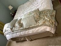 Overall view of the bed showing white fitted sheet, comforter, matching pillows and throw cushions