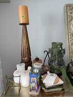 Photo showing the wooden candle holder with beige pillar candle, white candles, a set of coasters, and other smaller decorative items around the carved jade vase.