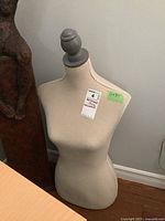 Photo of a lightweight cloth covered dressmaker's Judy measuring 16x30 with a grey painted round top knob, standing on wood floor.