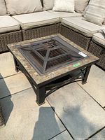 Angled front view of the fire pit table with mesh cover installed