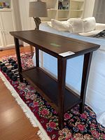 Front and side view of the wood hall table showing the inlay top and lower shelf on a floral rug background.