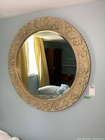 Front view of large round mirror with ornate carved frame on wall
