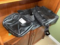 Photo of three black leather professional bags laid on a wooden surface, showing size and shape differences.