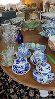 Photo of table showing four blue and white porcelain lidded teacups and saucers, clear glass cups, vases, and salt and pepper shakers on tray