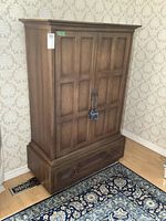 Front view of tall oak dresser with closed double-panel doors and single bottom drawer