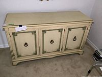 Front view of the painted sideboard showing three cabinet doors with green decorative trim and metal ring pulls.