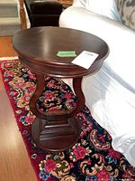 Full view of the dark wood pedestal plant stand or side table showing its shape, finish, and structure.