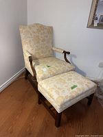 Full view of the vintage arm chair with matching ottoman on hardwood floor near white wall.