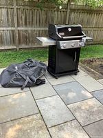 Full view of grill on patio with folded black cover beside it.
