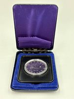 The presentation case open showing the coin in a plastic capsule.
