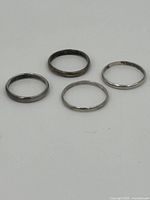 Four sterling silver rings laid flat showing wear and tarnishing.