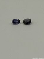 Two oval-cut alexandrite gemstones on white background showing color and cut details.