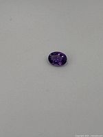Top view of the oval faceted purple amethyst gemstone on neutral background