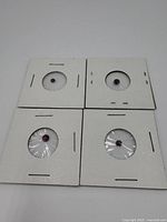 Overview of four individual amethyst stones mounted on white cardboard, each covered with plastic wrap.