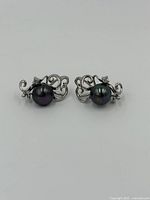 Front view of both black pearl sterling silver stud earrings showing the dark, lustrous pearls and intricate silver swirls with small stones.