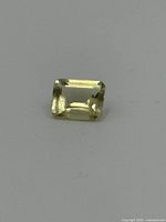 Top view image displaying the rectangular emerald cut of the light yellow citrine gemstone with visible facet reflections.
