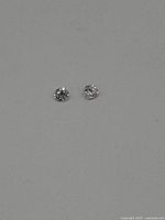 Two loose round brilliant cut diamonds on a plain background showing top view.