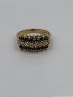 Front view of gold vermeil ring with emerald and cubic zirconia stones arranged in three rows