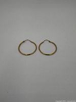 Pair of small gold hoop earrings on a plain surface, front view