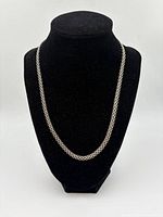 Full view of the silver chain displayed on a black mannequin bust showcasing length and chain type.