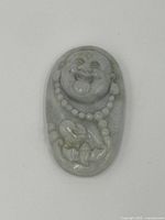 Front view of the oval jade pendant carved with a smiling Buddha and bead necklace detail.